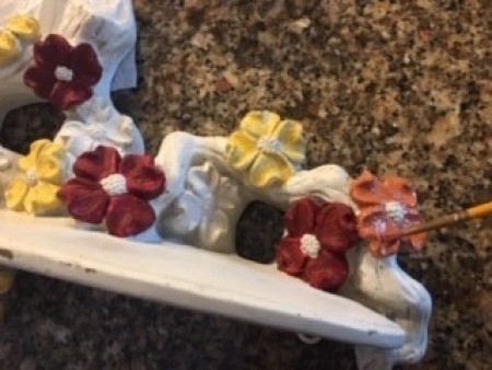 Painting the individual flowers on a ceramic shelf.