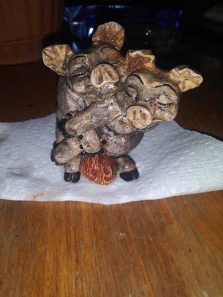 A figurine of two pigs cuddling.