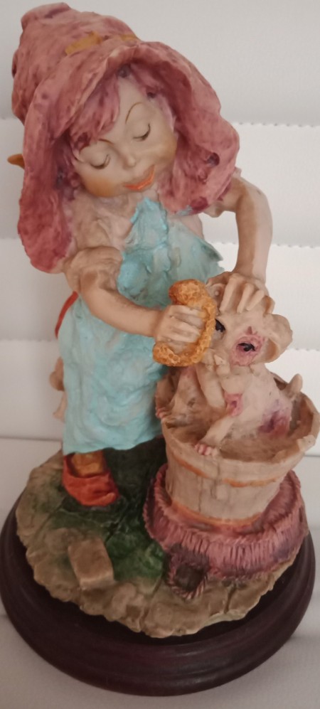 A small figurine of a girl bathing a puppy.