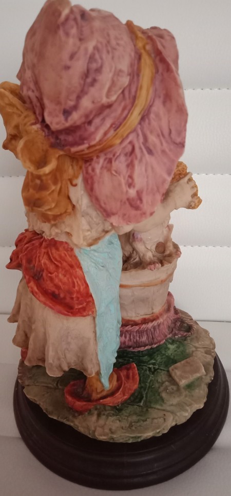 A small figurine of a girl bathing a puppy.