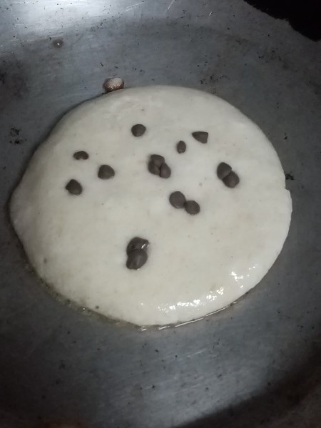 Adding chocolate chips to the pancakes.