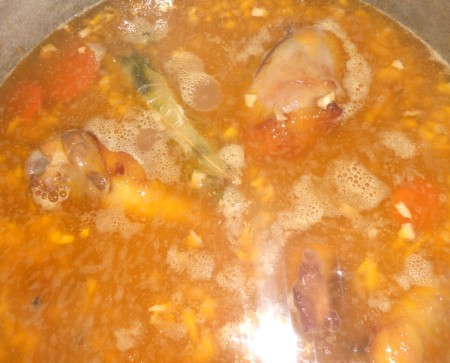 Cooking the browned chicken in the wine marinade, with vegetables.