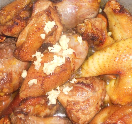 Adding garlic to the chicken pieces.