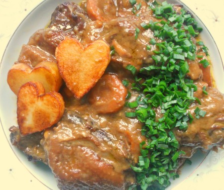 A plate of coq a vin with fried potatoes.