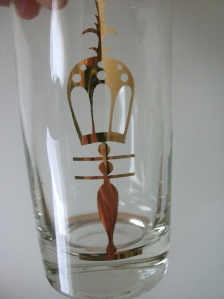 A drinking glass with a gold emblem.