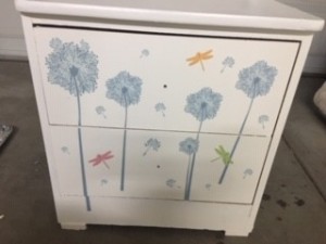 A white dresser with sticker designs on the front of the drawers.