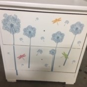 A white dresser with sticker designs on the front of the drawers.