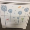 A white dresser with sticker designs on the front of the drawers.