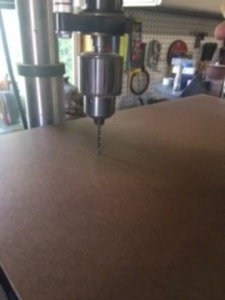 Drilling holes in the piece of wood.