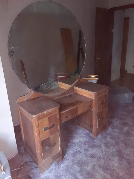 A vintage dresser with a large round mirror.