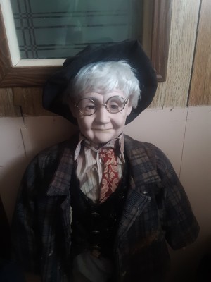 A doll dressed like an old man in a suit with glasses.