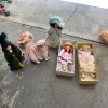 Six porcelain dolls on a driveway, two in boxes.