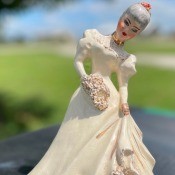 A figurine in an old fashioned dress.