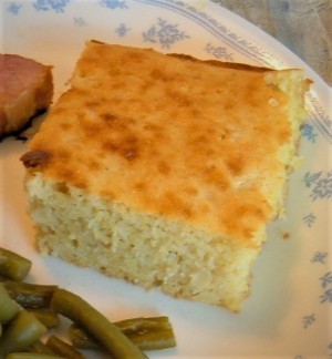 A piece of cornbread on a dinner plate.