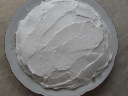 Covering the cake in whipped cream.