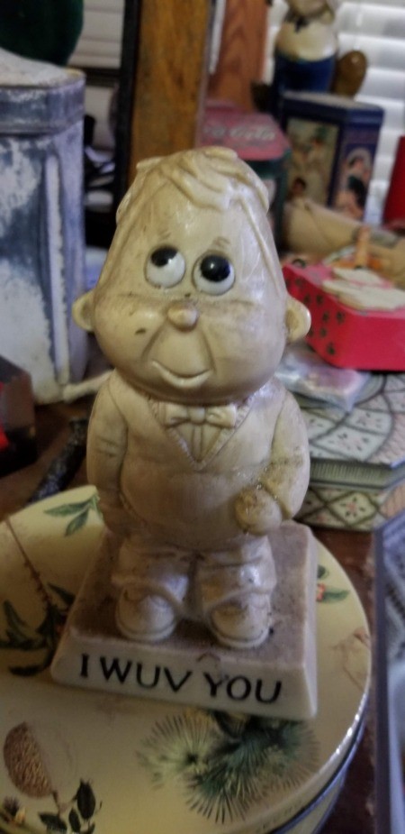 A figurine of a big eyed person saying "I WUV YOU."