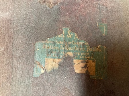 A worn label on the bottom of an old rocking chair.