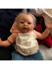 A baby doll with blonde hair and pink and white shirt.
