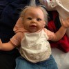 A baby doll with blonde hair and pink and white shirt.