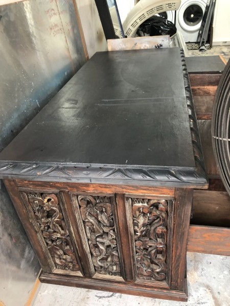 The side of a ornately carved wooden desk.