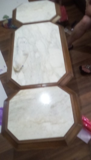 A long wood coffee table with white marble inlays.