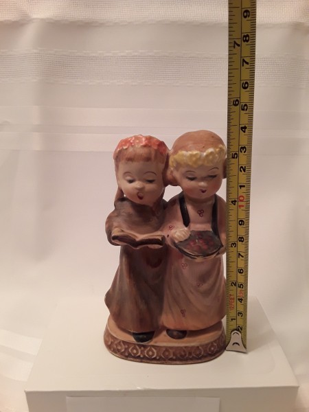 A figurine of two girls, measuring 5 1/2 inches tall.