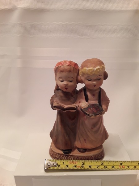 A figurine of two girls, measuring 3 inches wide.