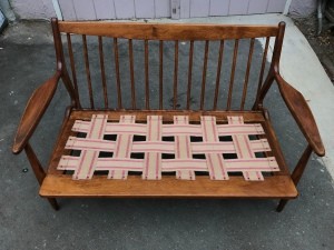 A wooden sofa with a woven seat.