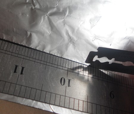 Cutting aluminum foil in a straight line.