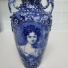 A blue and white vase with an old fashioned ladies face.