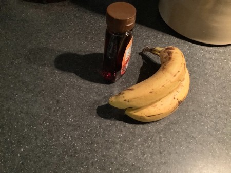 Bananas and maple syrup on a countertop.