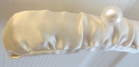 A satin hanger with pearl buttons on the shoulders.