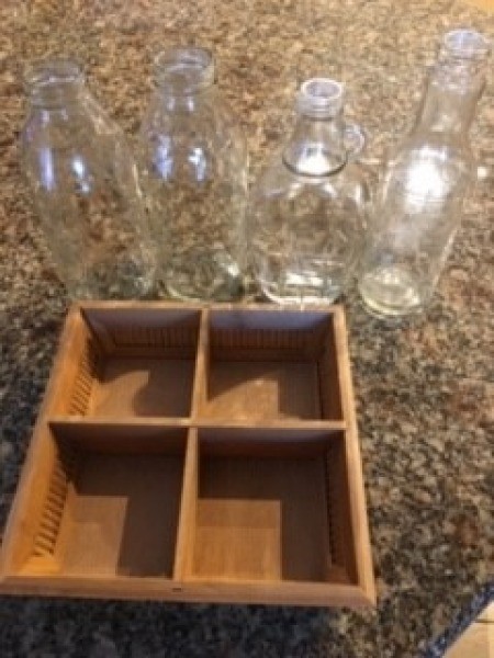 A small container with four sections and four clear glass bottles.