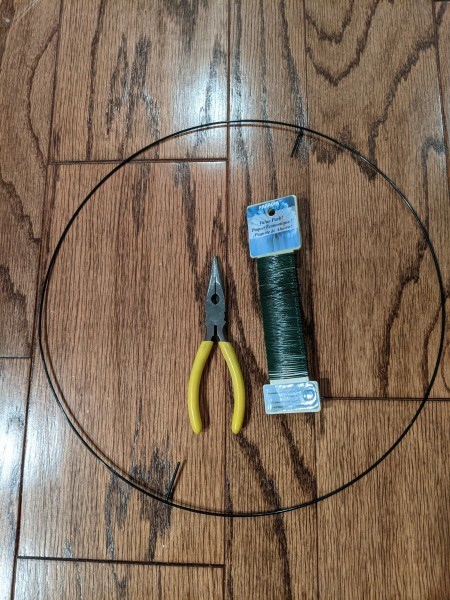 The circle wreath form, pliers and a spool of green wire.