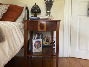 A small wooden end table next to a bed.