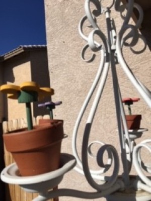 Wooden daisy flowers in terra cotta pots on a chandelier outside.