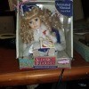 A boxed doll wearing a blue and white outfit.