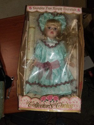 A boxed doll wearing a turquoise dress.