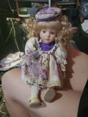 A porcelain doll wearing purple and white.