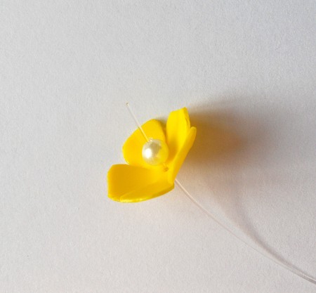 Adding a pearl to the center of the flowers.