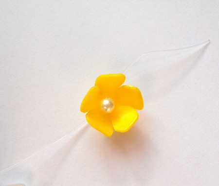 Adding a pearl to the center of the flowers.