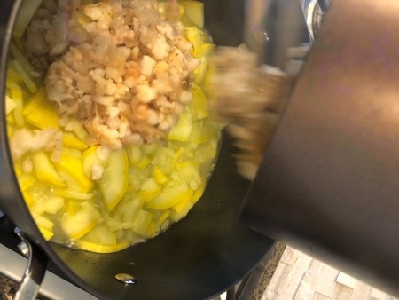 Adding the mixture to a stockpot with yellow zucchini.