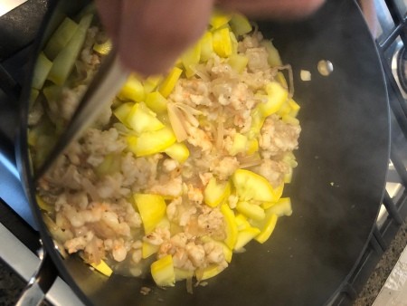 Adding the mixture to a stockpot with yellow zucchini.