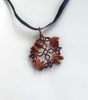 The completed pendant on a ribbon.