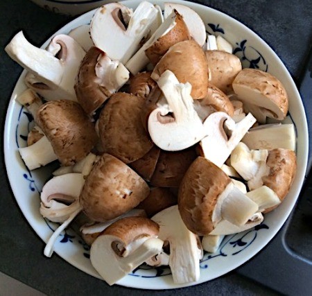 A bowl of cut up mushrooms.