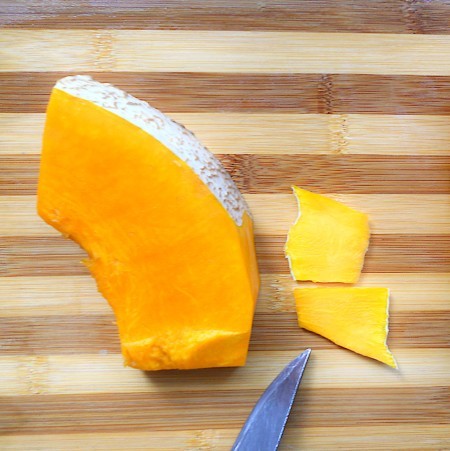 Removing the rind from a piece of pumpkin.