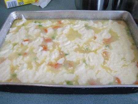 Placing the crust on the top of the pot pie.