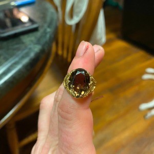 A gold ring with a large reddish stone.