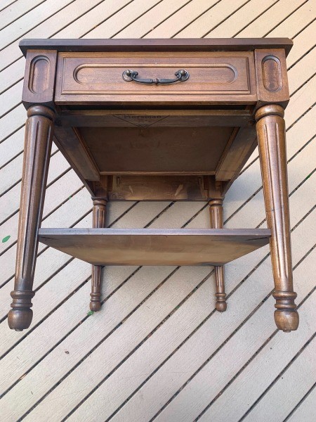 A wooden side table with a drawer.