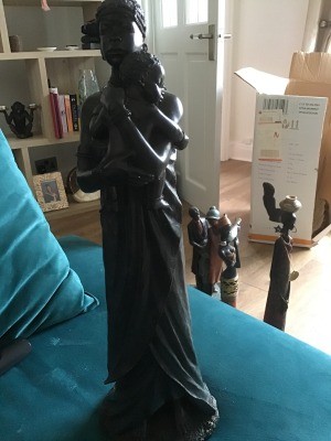 A dark wood colored figurine of a mother and child.